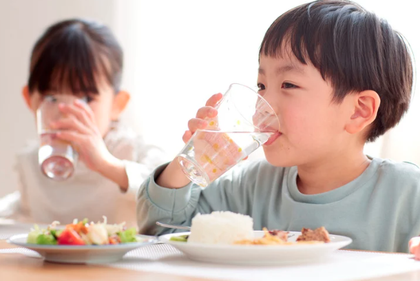 Child drinking large while ignoring meal on plate.